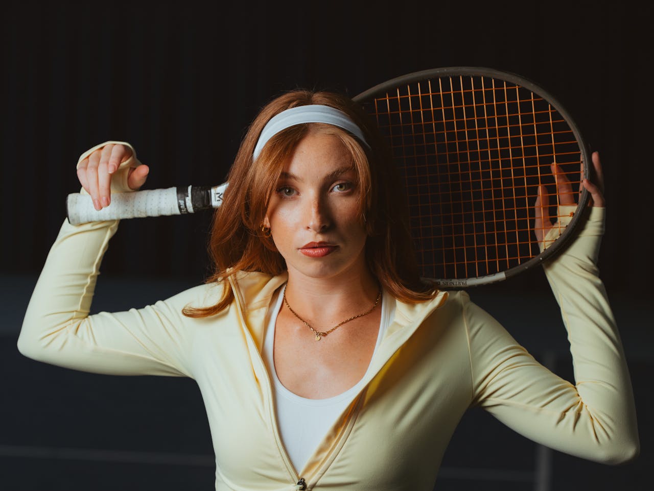 Confident female tennis player holding a racket, ready for action on the court.