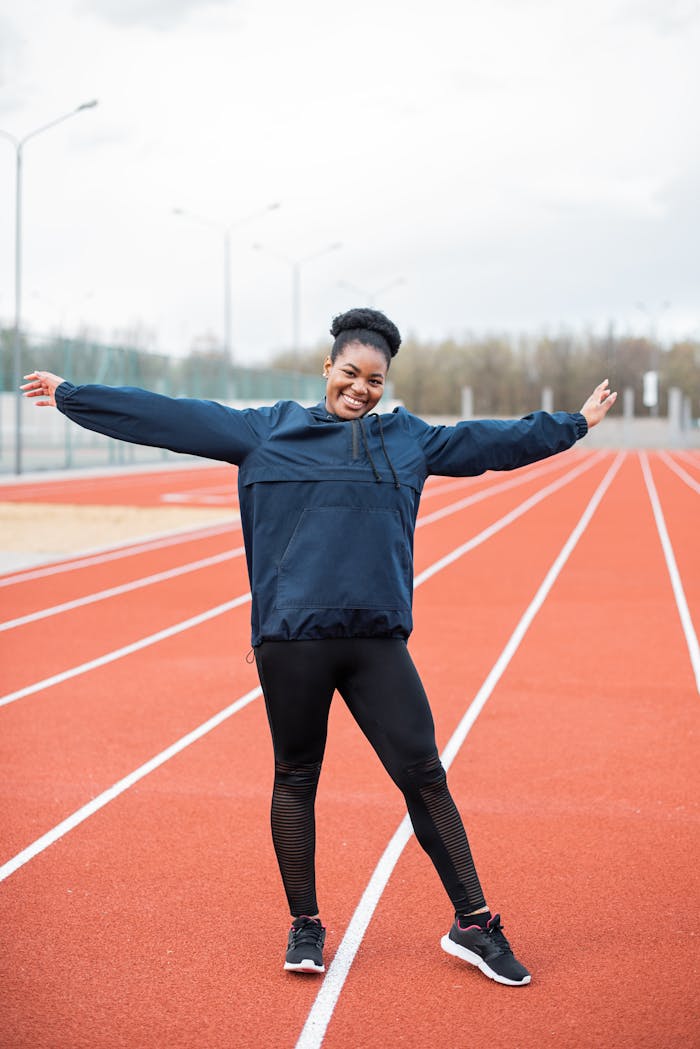 Smiling woman in sportswear enjoying a moment on the running track outdoors.